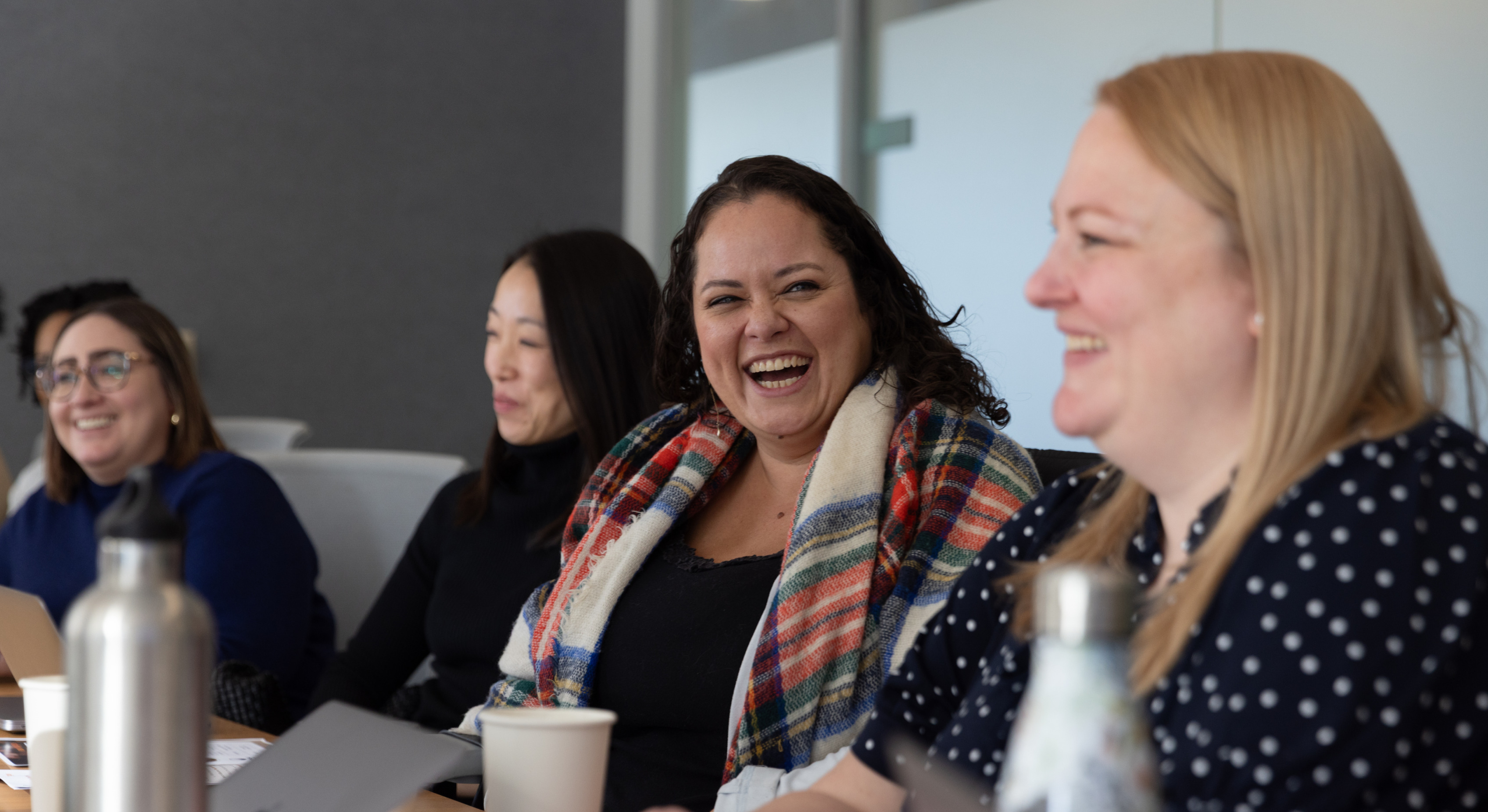 Alt Text: "Colleagues laughing together in an office conference room.
